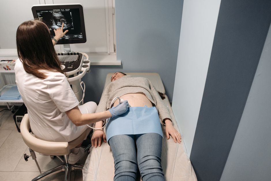 Healthcare professional performing a fertility ultrasound scan on a patient during an infertility workup consultation.