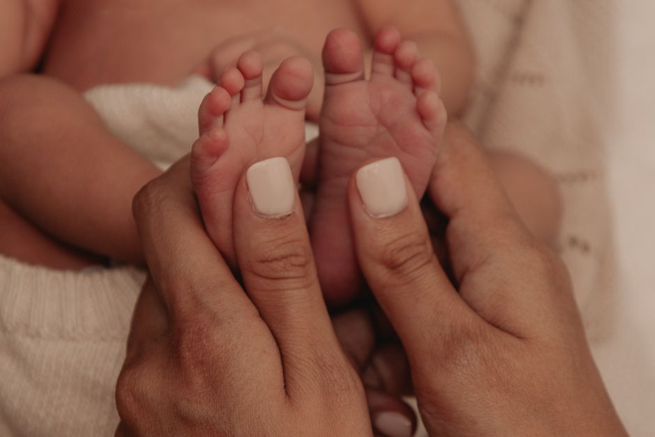 Close-up of a mother gently holding her newborn baby's hand
