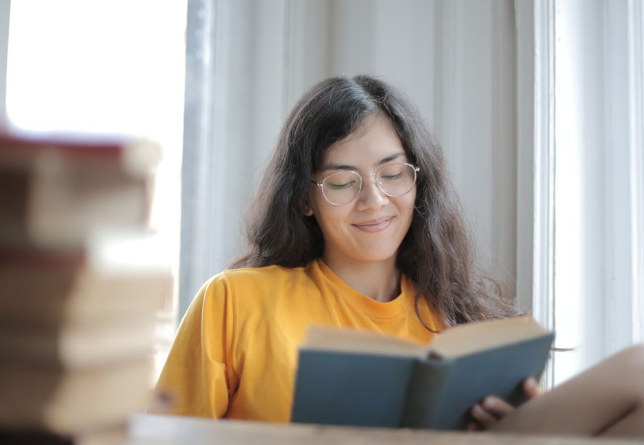 Woman reading calmly in a chair beside a sunny window