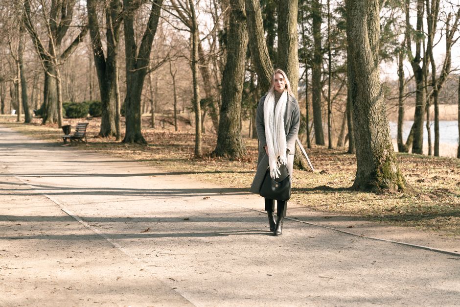 Woman taking a calm walk through a park with fall leaves