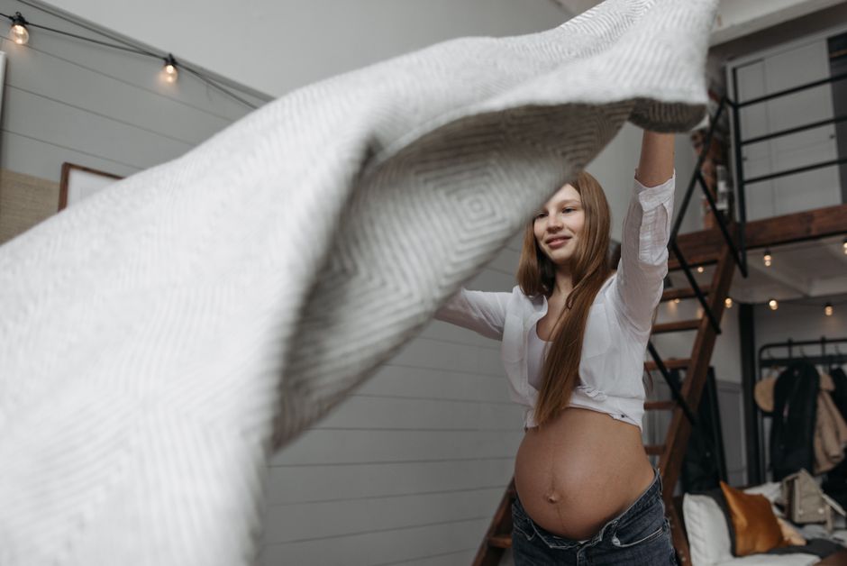 Pregnant woman relaxing at home wrapped in a cozy knit blanket
